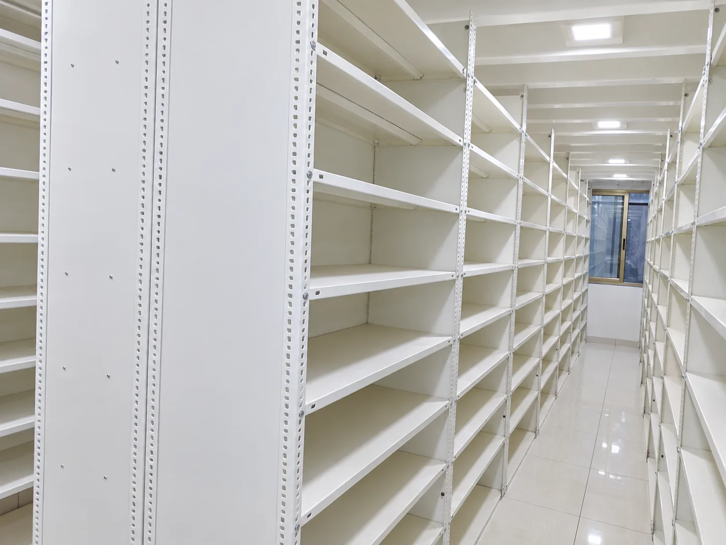 White storage shelves arranged along an aisle.