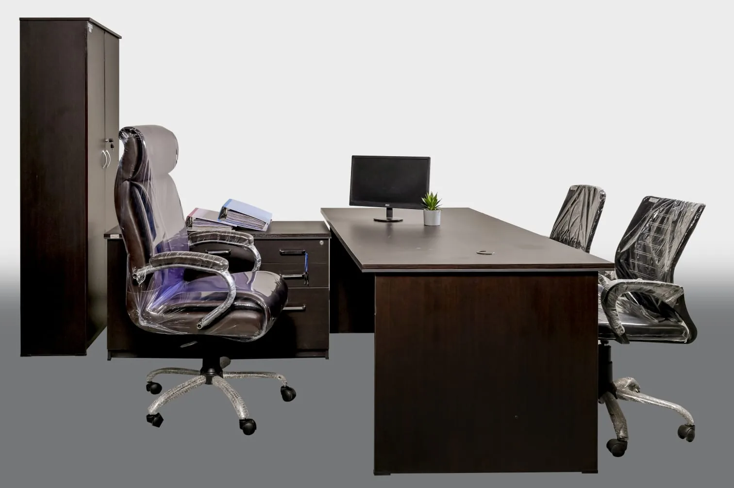 An office bay: desk, visitor chairs and a steel cupboard behind.