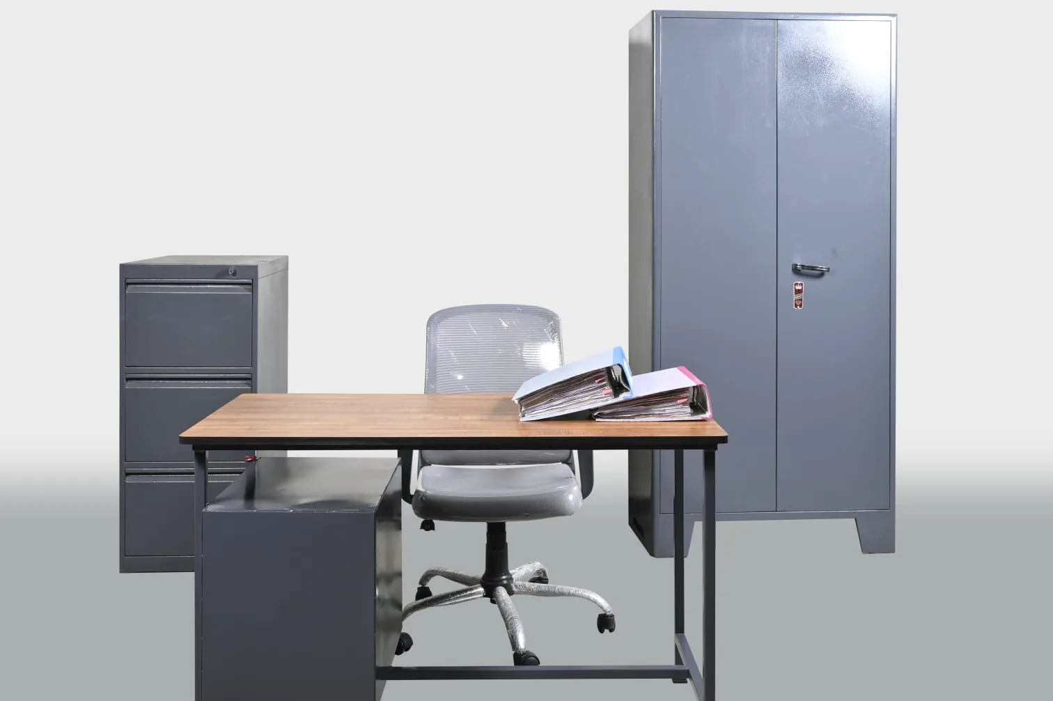 A working office: desk, chair, filing cabinet and a steel almirah.